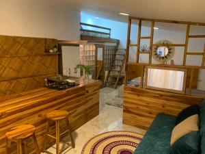 sala de estar con paredes y taburetes de madera y TV en ROOM LA ISLA, en Ayampe