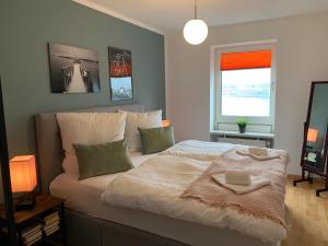 ein Schlafzimmer mit einem Bett mit einer Decke und einem Fenster in der Unterkunft Strand-Apartment, Strandkorb, Meeresrauschen, Parkplatz in Wilhelmshaven