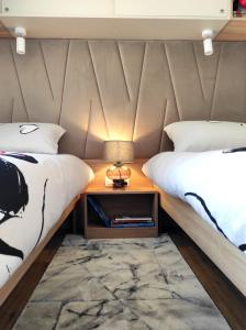 1 dormitorio con 2 camas y mesita de noche con lámpara en Zen Zone Premium Mobile Home en Drage
