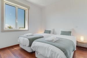 two beds in a white room with a window at Bela São Tiago I in Funchal