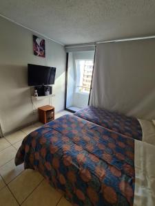 a bedroom with a bed and a flat screen tv at Frente Al Parque Arauco in Santiago
