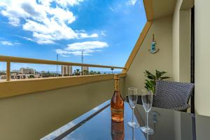 un tavolo con bicchieri e una bottiglia di vino sul balcone di Newly reformed apartment with sea view and pool, near the beach, in Playa de Las Americas a Playa de las Americas