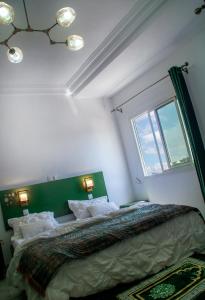 a bedroom with a bed with a green headboard and a window at Johen Residence in Douala