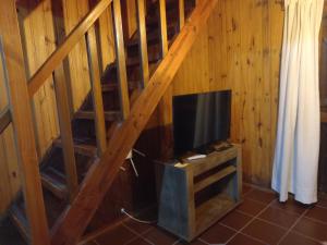 a tv sitting on a stand under a wooden staircase at Maneki in La Paloma