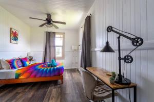 Schlafzimmer mit einem farbenfrohen Bett und einem Schreibtisch in der Unterkunft Somewhere over the Rainbow Loft with AC Hilo in Hilo