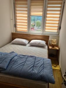 a bedroom with two beds and a window with blinds at Bilino polje in Zenica