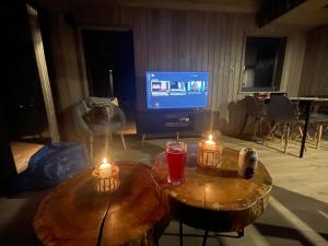 dos mesas de madera con velas delante de una televisión en Szopa_Narie, en Gulbity