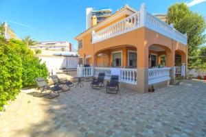 a house with chairs on a patio in front of it at Great villa, Sea views, 20 secs walk to the beach, BBQ, 9 people, 5 mins car from Alicante city center, sailing club 3 mins walk in Alicante
