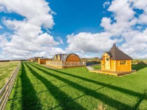 a large grass field with a building in the distance at Caithness View Luxury Farm Lodges and BBQ Huts in Wick