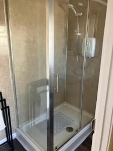 a shower with a glass door in a bathroom at Bells Yard cottage in Maryport