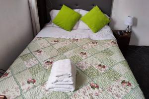 un letto con cuscini e asciugamani verdi di Casa Artesana a Cuzco