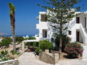 a view of a white building with trees and flowers at Village Twins in Ios Chora