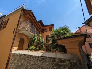 a building with a balcony and palm trees on it at Antica Osteria Apartments in Dongo