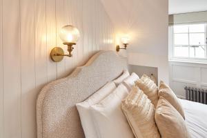 a bedroom with a bed with white pillows and lights at Boutique Fisherman’s Cottage in Cullercoats +15 photos