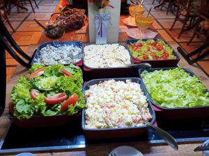 una mesa cubierta con bandejas de diferentes tipos de alimentos en Villa'l Mare Hotel, en Maresias