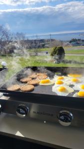 a grill with eggs and hamburgers on it at Bryson's Bed and Breakfast in Baddeck