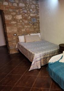 ein Schlafzimmer mit einem Bett und einer Steinmauer in der Unterkunft La taverna sotto la torre in Massa Marittima