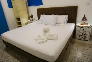 a bedroom with a large white bed with towels on it at Hotel casa Narvaez in Girardot