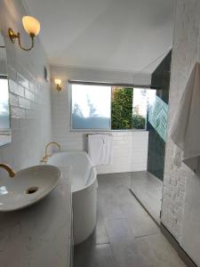 uma casa de banho branca com um lavatório e uma banheira em Windarra on High em Launceston