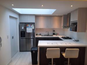 a kitchen with a refrigerator and a counter with chairs at Acogedora Casa Comoda y Tranquila a 5 min del Turi in Cuenca