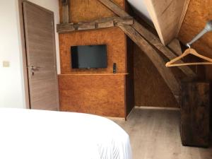 1 dormitorio con 1 cama y TV en el ático en Le Temps d'un Souffle - Gîte rural 3 épis, en Sivry