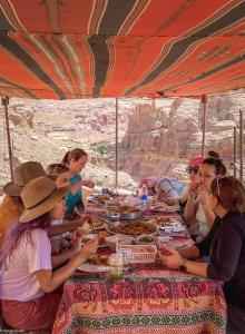 a group of people sitting around a table eating food at Indiana Jones Cave in ‘Ayn Amūn