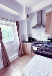 a kitchen with a sink and a stove and a window at Charming Studio Flat with Private Patio Balcony in the Heart of Chelsea in London