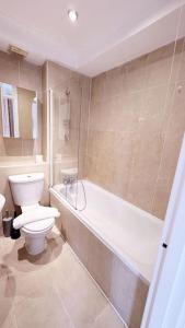 a bathroom with a toilet and a tub and a sink at Charming Studio Flat with Private Patio Balcony in the Heart of Chelsea in London
