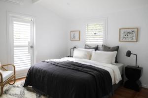 a white bedroom with a large bed and two windows at Sirens in Byron Bay