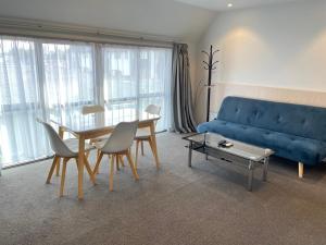 a living room with a blue couch and a table at 2 on Whiteleigh and 239 on Lincoln Motel in Christchurch