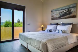 a bedroom with a large bed and a large window at Alekos Beach Houses-Profilio's Villas in Lixouri