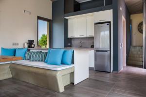 a kitchen with a bench with blue pillows on it at Alekos Beach Houses-Profilio's Villas in Lixouri