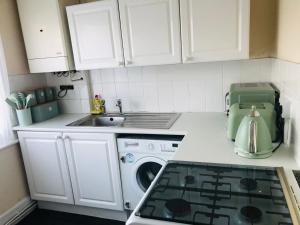 a kitchen with a stove top oven next to a washing machine at AC Lounge 119 in Rochford