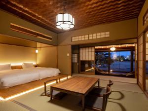 sypialnia z łóżkiem i drewnianym stołem w obiekcie Ryokan Onomichi Nishiyama w mieście Onomichi