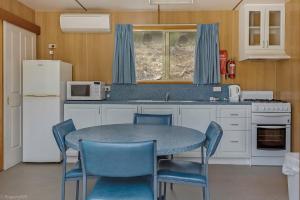uma cozinha com uma mesa e cadeiras e um micro-ondas em Hobart Bush Cabins em Kingston