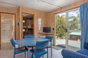 Habitación con mesa, sillas y puerta corredera de cristal. en Hobart Bush Cabins, en Kingston