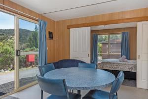 a dining room with a table and chairs and a bedroom at Hobart Bush Cabins in Kingston