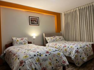 a hotel room with two beds and curtains at Hostal Inkanto Taruma in Tarma