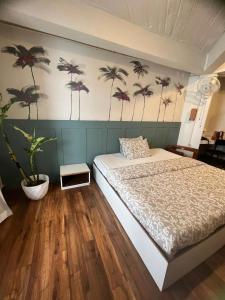 Schlafzimmer mit einem Bett und einem Wandbild von Palmen in der Unterkunft Jojos Nascere in Aizawl