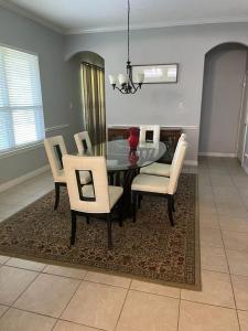 une salle à manger avec une table en verre et des chaises blanches dans l'établissement A perfect getaway in Cinco Ranch, Texas., à Katy