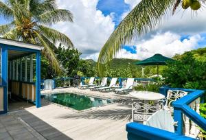 a pool with chairs and a table and an umbrella at Little Rock Cottage in Cobbs Cross