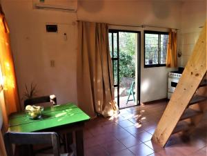 a dining room with a green table and a kitchen at Colibrí Apart in El Soberbio