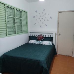 a bedroom with a bed with green sheets and birds on the wall at Recanto Panapaná - suítes in Águas de São Pedro