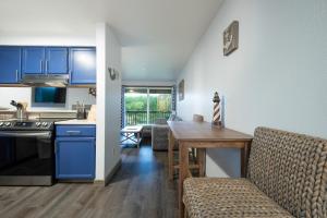 a kitchen and dining room with blue cabinets and a table at Aurora at Nautilus - Pet Friendly Oceanfront Condo in Ocean Shores