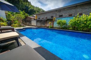 a large blue swimming pool next to a building at Family Garden Homestay in Senggigi