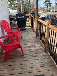 2 chaises rouges assises sur une terrasse en bois dans l'établissement 2 bedroom, sleeps 7 in Wasaga Beach, à Wasaga Beach