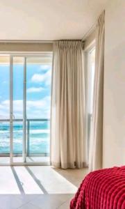 Schlafzimmer mit einem großen Fenster mit Meerblick in der Unterkunft Amazing Ocean Front Condo in Rosarito