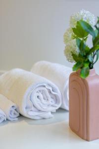 een vaas met bloemen erin naast handdoeken bij Inner City Luxury 2 Bedroom 2 Bathroom in Christchurch