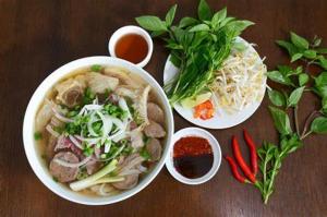 un tavolo con due ciotole di zuppa e alcune verdure di Thuy Loi Hotel a Hoi An
