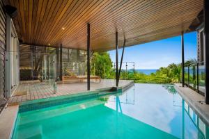 a swimming pool in a house with a wooden ceiling at Elouera in Byron Bay